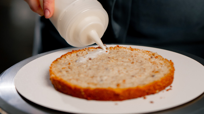 Someone applying a cake soak with a squeeze bottle