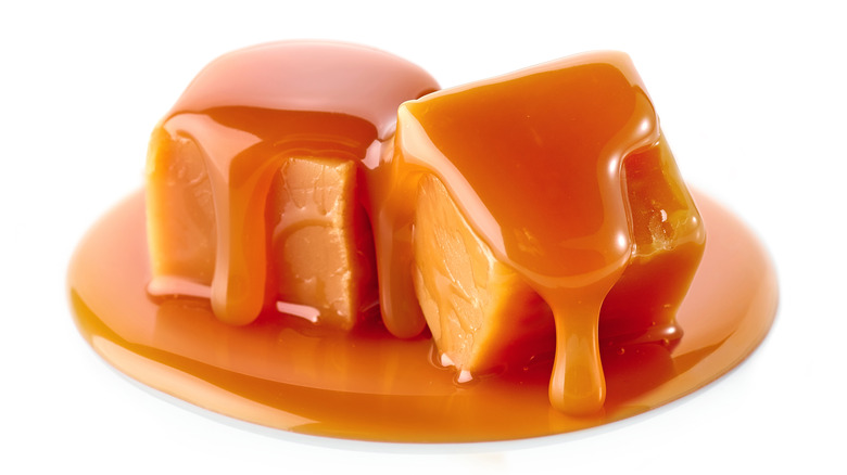 two caramel candies melting on a white background