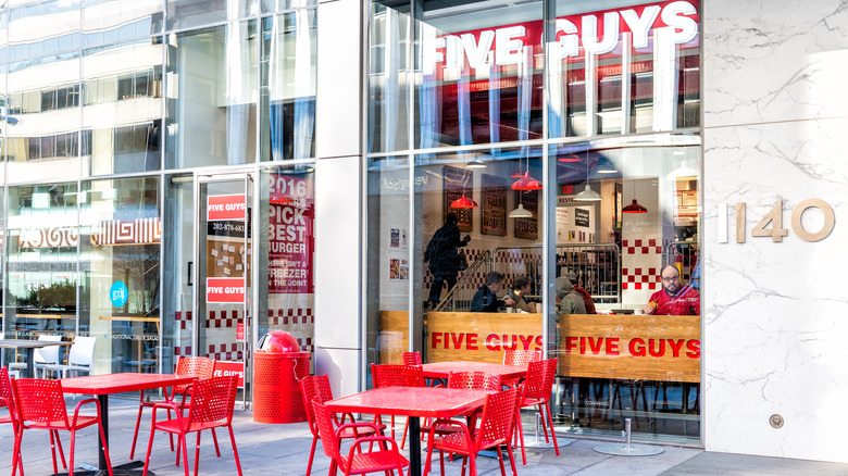 Five Guys restaurant view from outside, with orange tables on a patio.