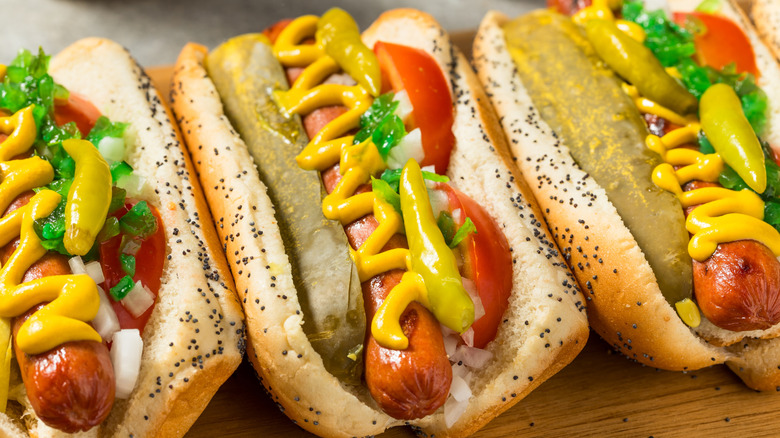 Chicago-style hot dogs with a sesame bun, mustard, tomatoes, onions, peppers, and more