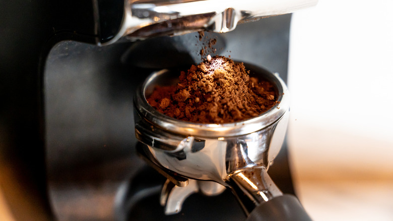 A coffee grinder dispensing a new espresso into a portafilter.