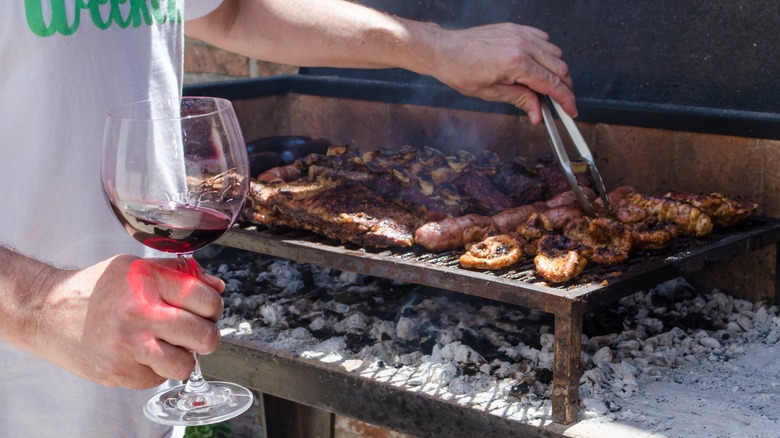 man grilling meats with red wine