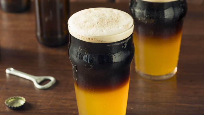 A pint of black and tan beer on a table.