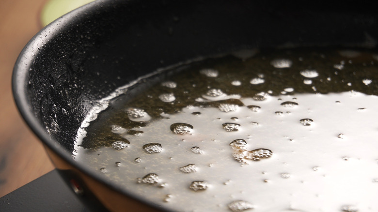 Used cooking oil bubbling in a skillet.