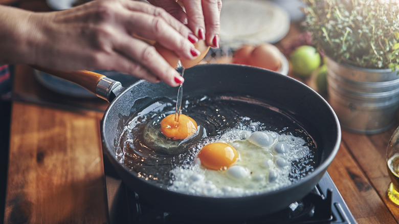 A person frying eggs in oil.