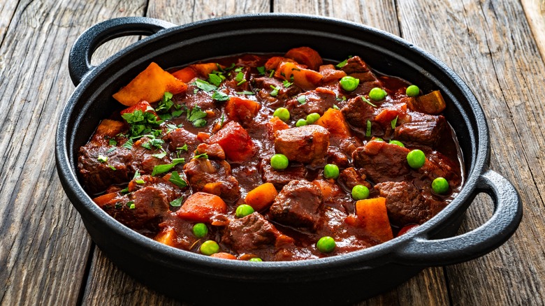 Cast-iron pot of beef stew on a wooden table