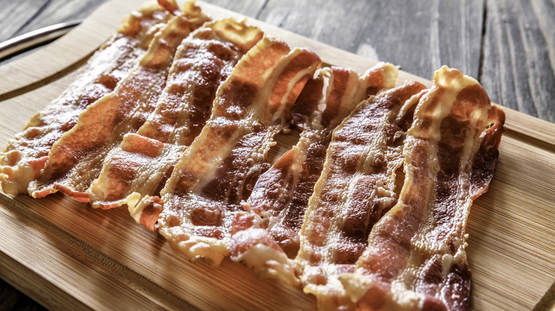 Cooked crispy bacon strips on a wooden board