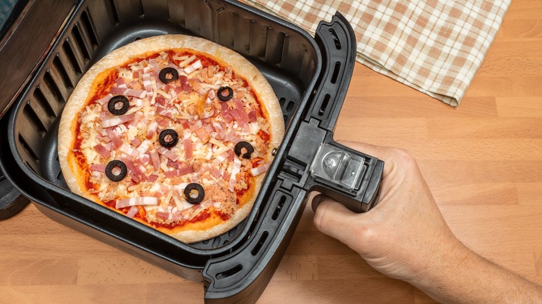 Placing a small pizza in an air fryer