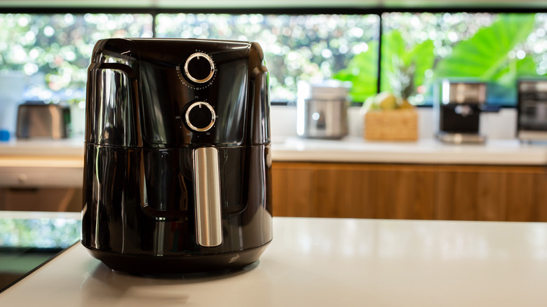 A black and silver air fryer sitting on a kitchen counter