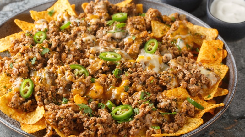 A platter of corn nachos topped with beef, cheese, and jalapenos