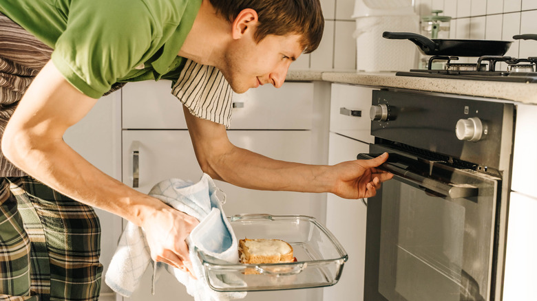 A man putting a baking tray into the oven.