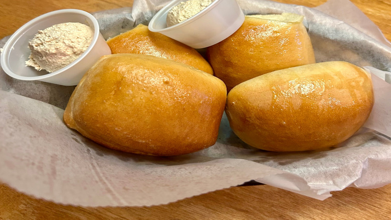 Texas Roadhouse rolls in a basket with small containers of cinnamon honey butter