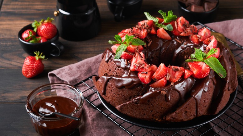 Chocolate bundt cake with chocolate icing, strawberries, and mint on top