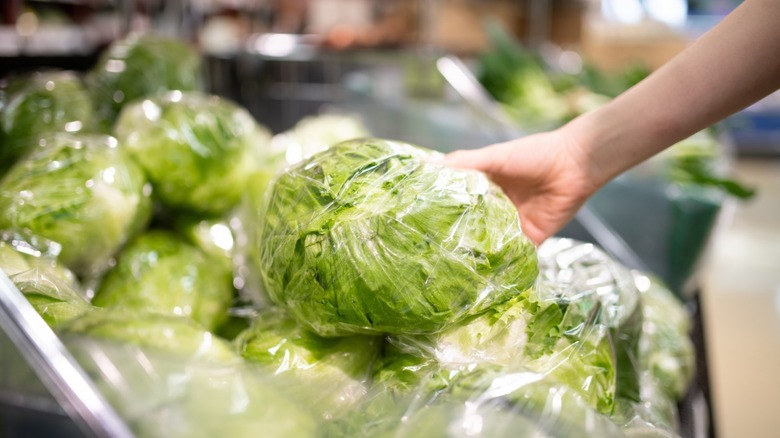 Choosing a head of lettuce from grocery display