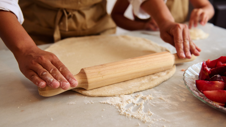 Rolling pie dough over counter surface