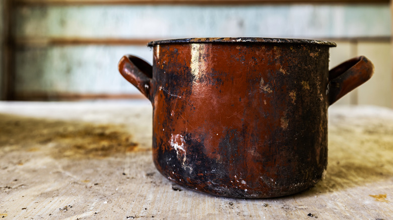 an old beat-up red pot on an equally dilapidated table