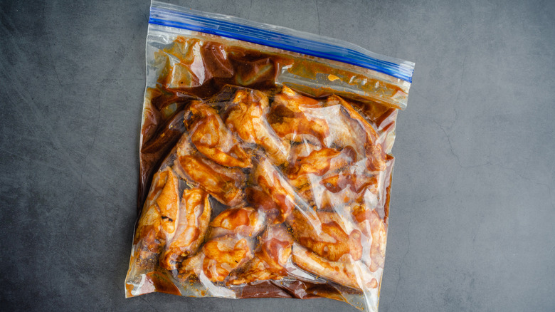 Pieces of chicken marinating in a ziploc bag