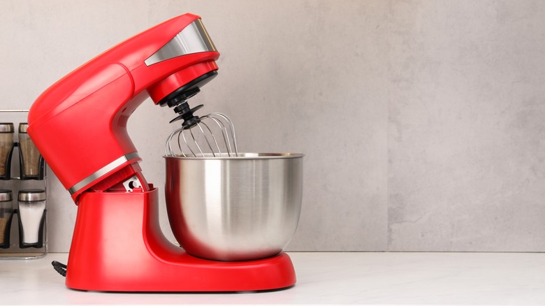 a red stand mixer against an off-white wall