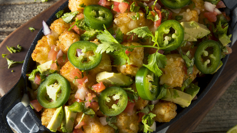 Tater tots topped with sliced fresh jalapeños, avocado, and pico de gallo