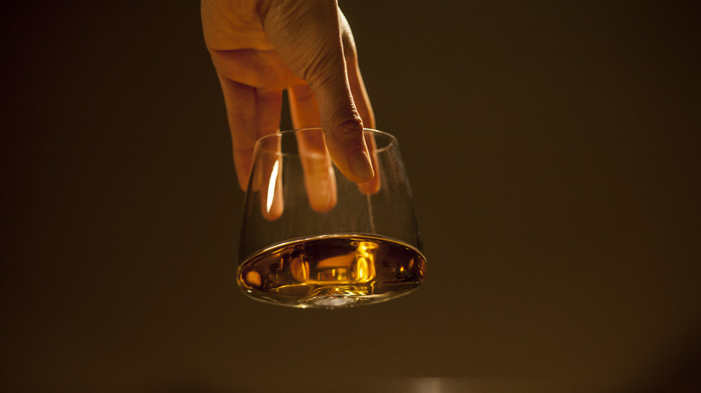 Hand holding whiskey glass