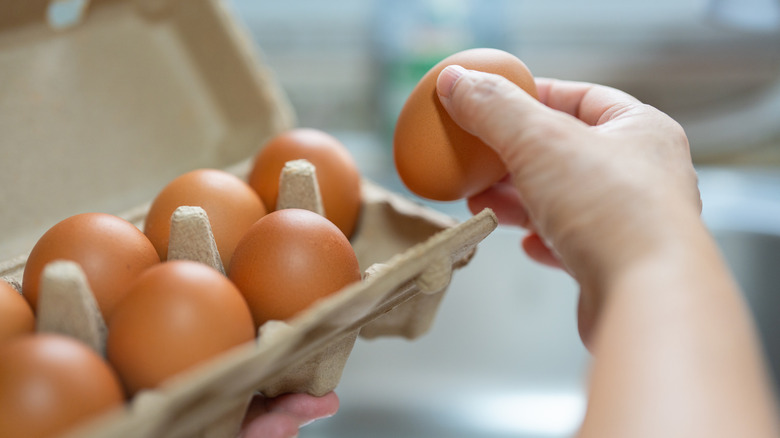 woman selecting egg from carton