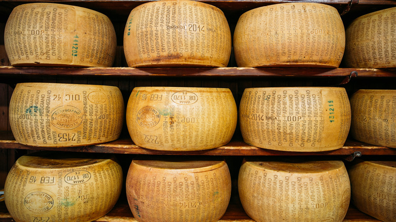 Wheels of parmegiano reggiano stacked on top of one another with a close-up of the rind