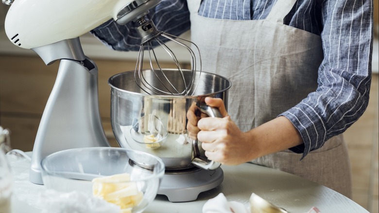 Women in apron uses a standing mixer to bake.