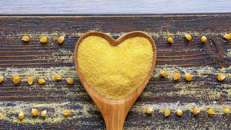 Heart shaped wooden spoon holding cornmeal