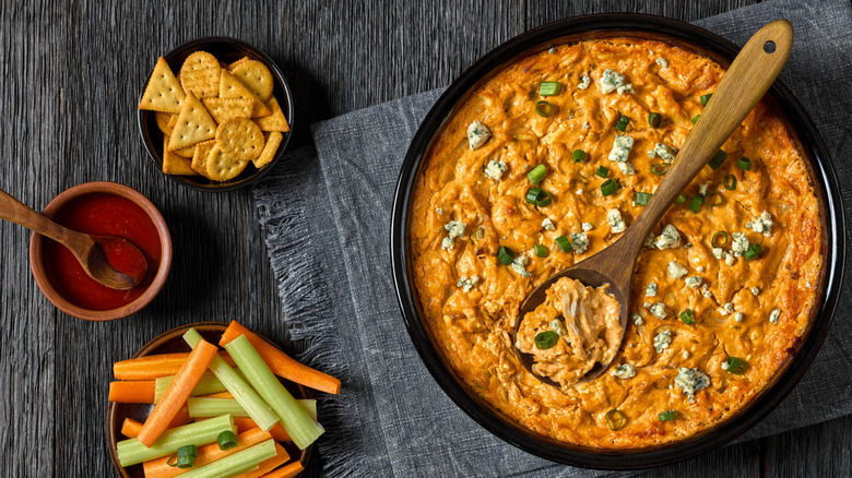 buffalo chicken dip with crackers, carrots, and celery sticks