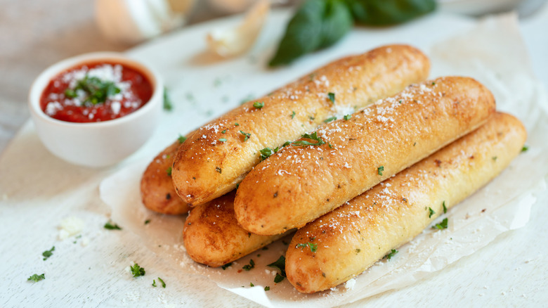 Seasoned breadsticks on a tray with marinara sauce nearby