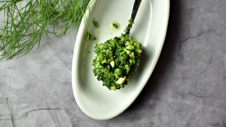 A spoonful of lush green chimichurri sauce in a white dish.