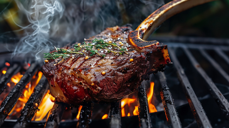 Tomahawk steak smoking on the grill