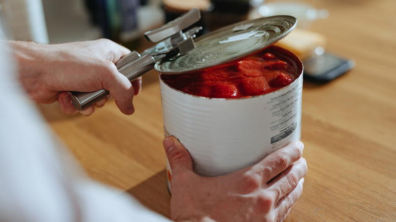 Person opening a can of whole tomatoes