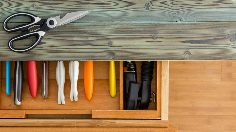 Kitchen shears sitting on a wood countertop next to an open drawer