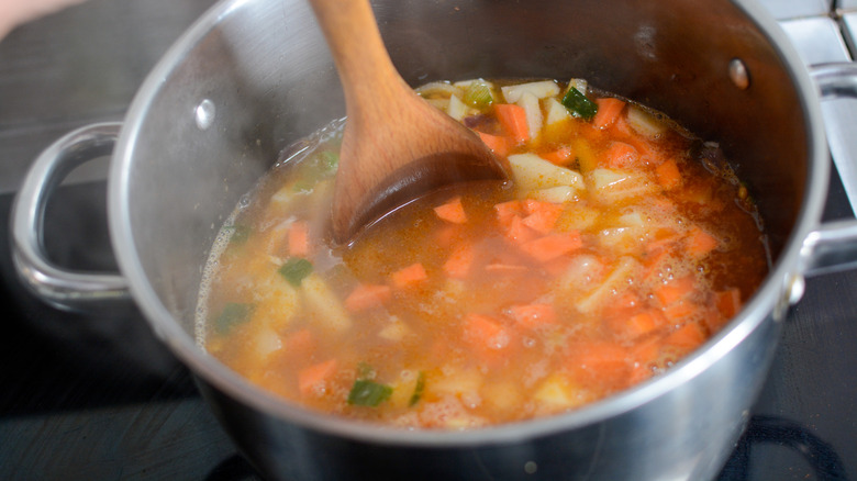 wooden spoon stirring vegetables in a soup pot