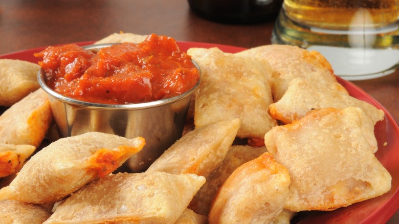 Pizza rolls on a plate with marinara dipping sauce.