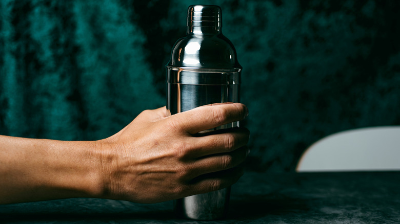 Hand holding a metal cobbler cocktail shaker