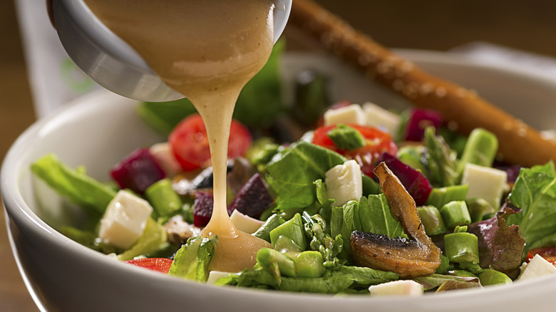 Vinaigrette being poured on a salad