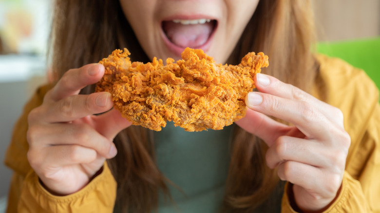 Person holding large piece of fried chicken