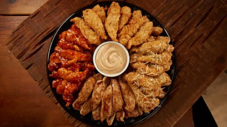 Huey Magoo's chicken tenders on circular plate with sauce