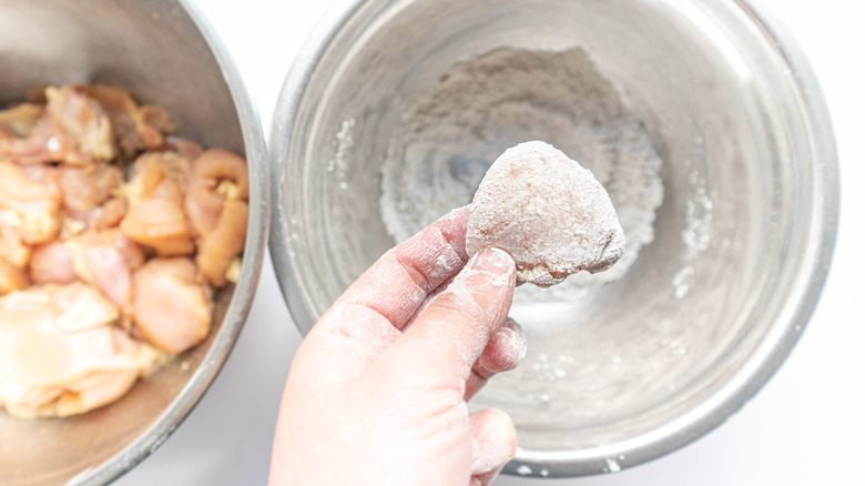 Person dredging chicken pieces in flour