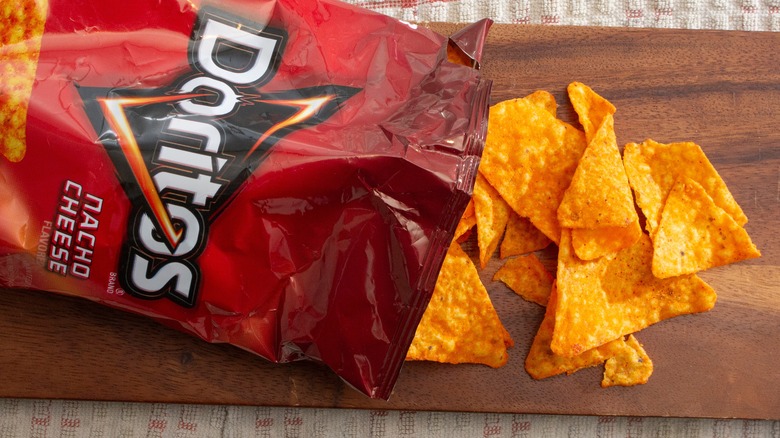 nacho cheese doritos spilling out of a bag onto a cutting board