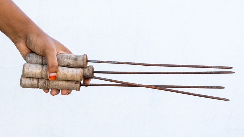 hand holding wood-handled skewers