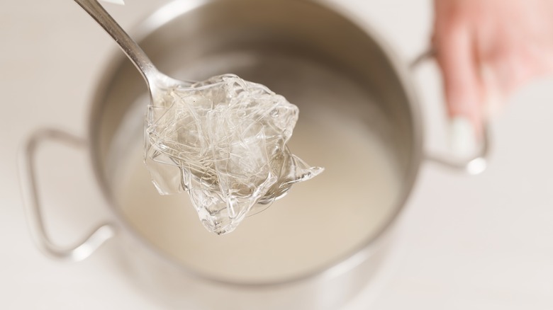 Clear gelatin on spoon above pot