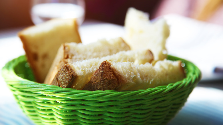 A green wicker basket filled with crusty white bread