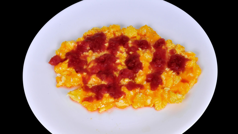 Scrambled eggs with salsa and cheese on a white plate