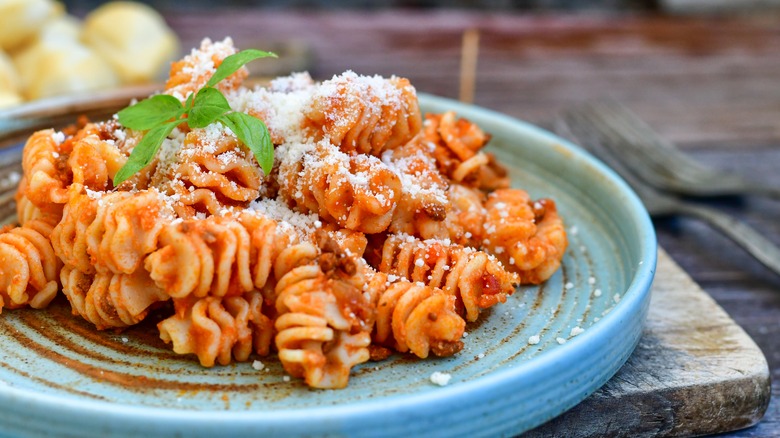 Radiatori pasta on a blue plate with red sauce and herb garnish