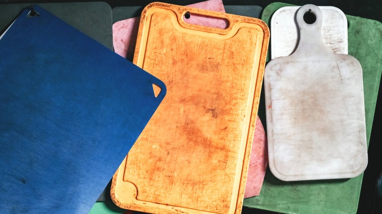 Several colorful used cutting boards stacked on top of each other.