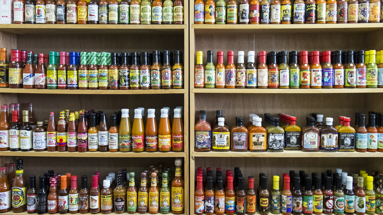 Grocery store shelves stocked with a huge range of hot sauce bottles