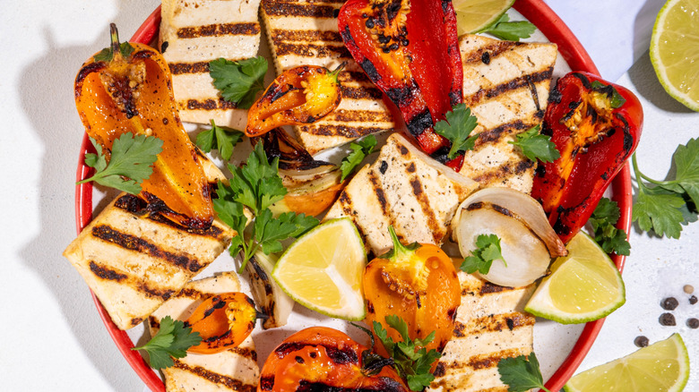 person using chopsticks to move tofu on grill